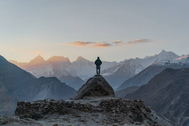 Man standing on rock and looking at river in Himalayas stock photo