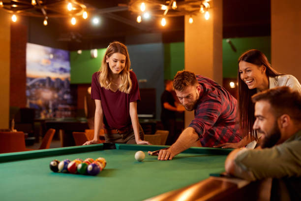 istock Group of friends having fun while playing pool in a local pool hall 1356410717