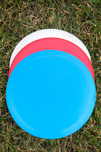 Various flying discs used for disc golf on green grass.