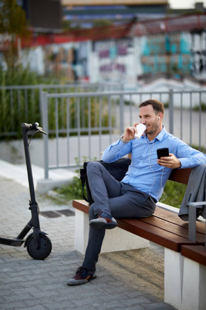istock Businessman with electric push scooter using mobile phone 1356412135