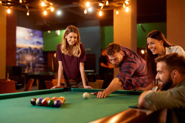 istock Group of friends having fun while playing pool in a local pool hall 1356412943