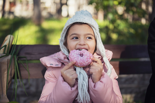 Cute girl enjoying pink glazed donut