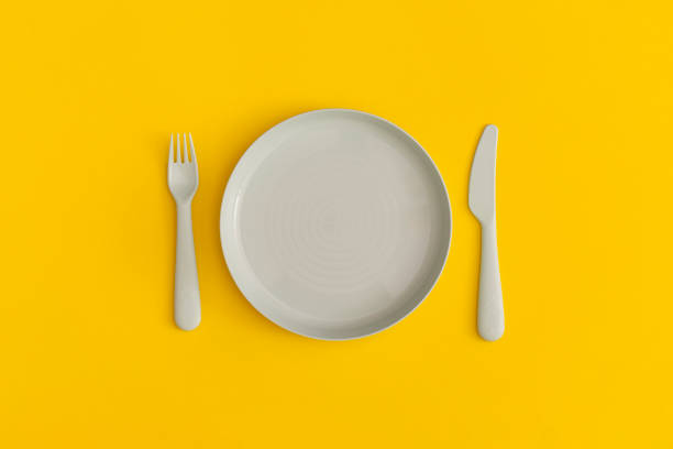 istock Blue plate with fork and spoon on a yellow background. Top view. Flat lay. 1356415233