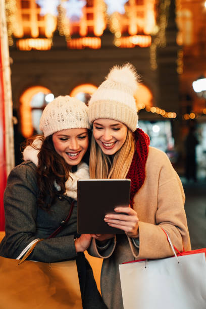 happy women friends enjoying shopping together outdoors. people christmas shopping tablet concept - ipad shopping gift retail imagens e fotografias de stock