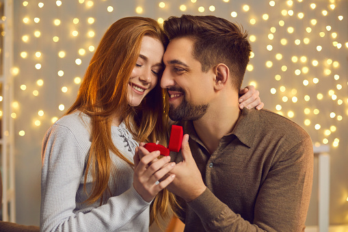 Happy couple in love hugging after woman said yes and accepted marriage proposal and diamond engagement ring from boyfriend. Man enjoying romantic date with girlfriend and giving her jewelry present