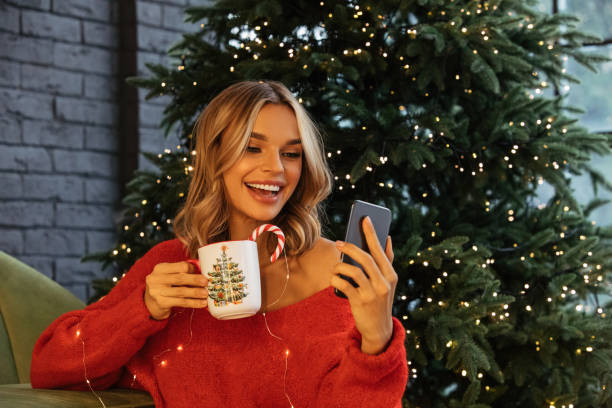 istock Woman using phone among Christmas atmosphere 1356421369