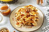 Banana waffles with walnuts and salted caramel in a plate on a culinary background