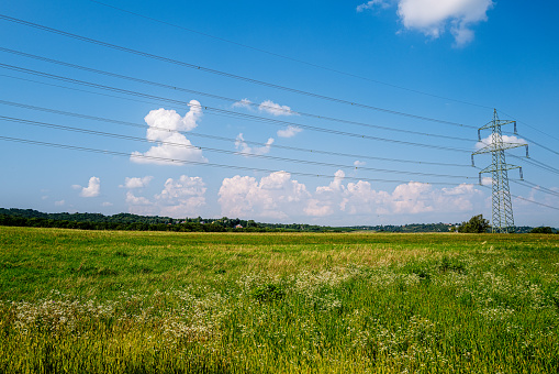 A high-voltage line stretches across a beautiful summer cultural landscape.