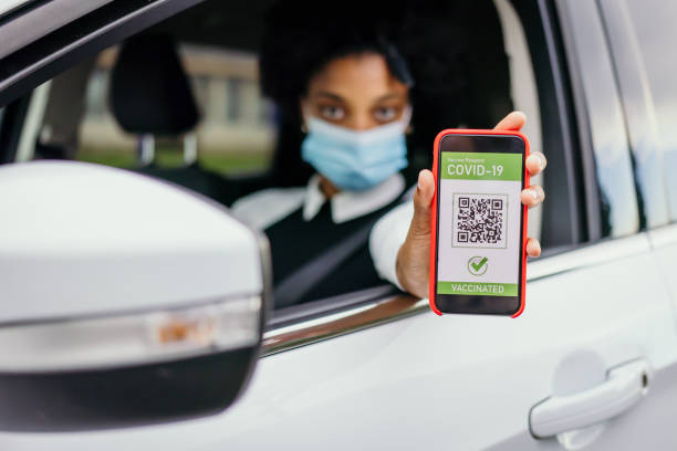 istock Female car driver holding a smartphone with a valid digital vaccination certificate for COVID-19 1356425473