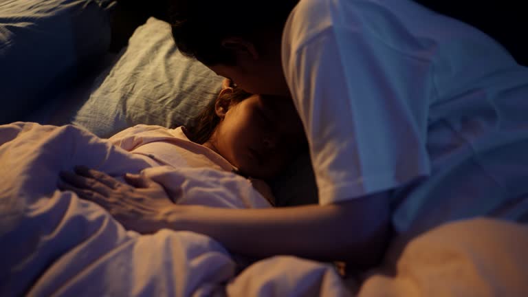 Asian baby or child girl sleeping with her pregnant mother in the bedroom at night.