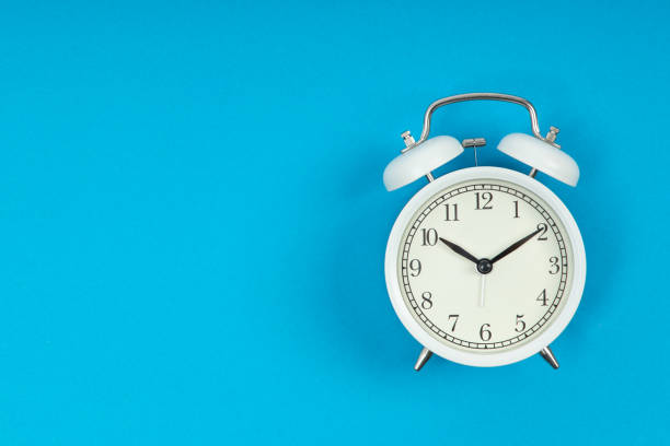 istock Retro alarm clock on blue background. Old fashioned alarm clock 1356428716