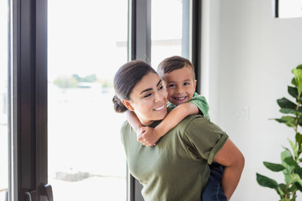 Happy little boy rides piggyback on his mom's back