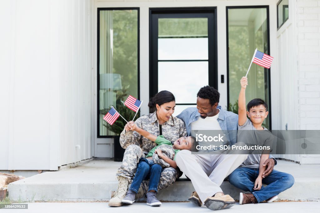 Female soldier is excited to be home with her family After reunited with her family, a female soldier enjoys spending time with them. Veteran Stock Photo