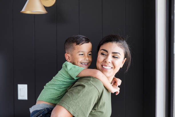 istock Little boy rides piggyback on his mom's back 1356430778
