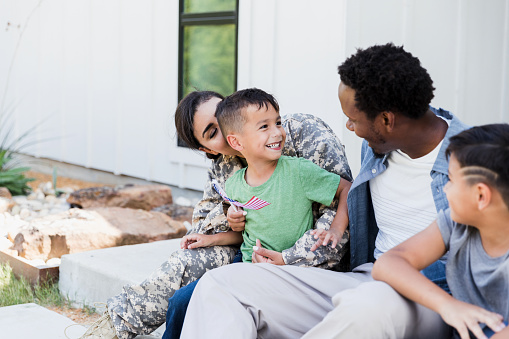 An adorable little boy smiles at his dad as they sit on the steps of their home.