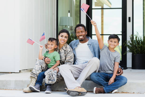 istock Sitting on front stoop, military family waves American flags 1356431007