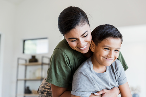 After returning from deployment, the mid adult female soldier gives her preteen son a big hug.