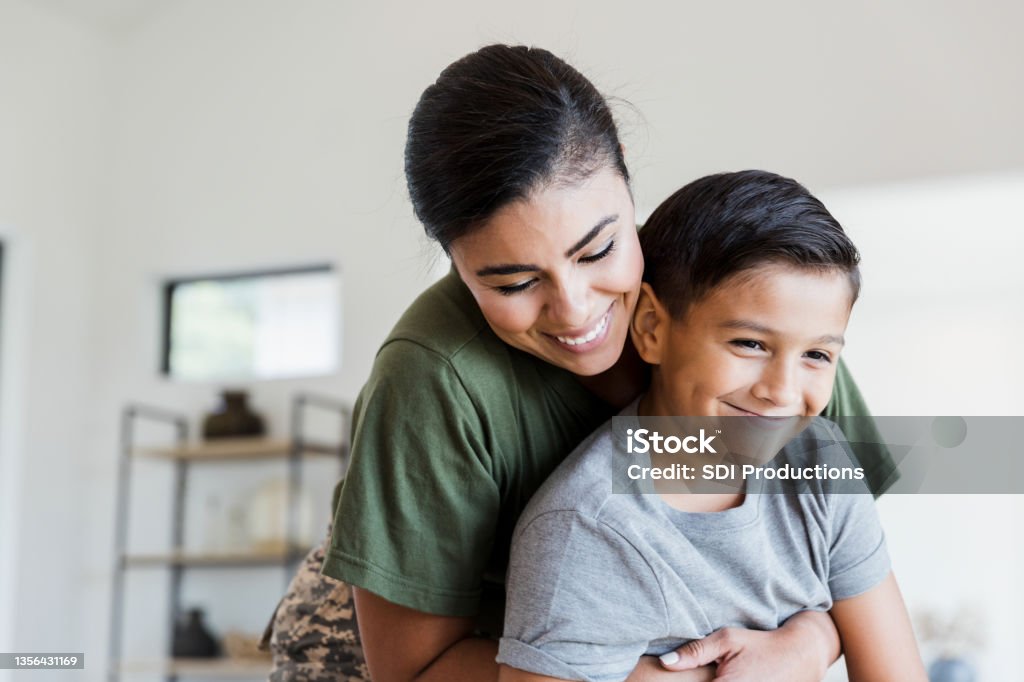 Soldier mom gives preteen son big hug After returning from deployment, the mid adult female soldier gives her preteen son a big hug. Family Stock Photo