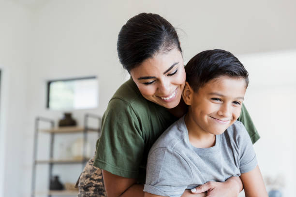 Soldier mom gives preteen son big hug After returning from deployment, the mid adult female soldier gives her preteen son a big hug. hispanic family stock pictures, royalty-free photos & images