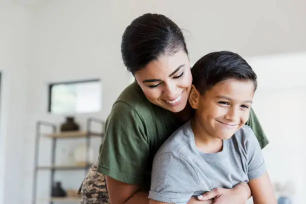 After returning from deployment, the mid adult female soldier gives her preteen son a big hug.