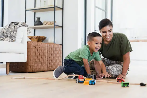 Photo of Sitting on floor, mom and son enjoy racing toy cars