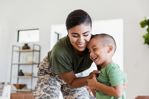 Mamá soldado juguetonamente le hace cosquillas a su hijo de primaria photo