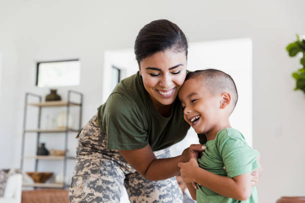 Soldier mom playfully tickles elementary age son The mid adult soldier mother playfully tickles her little boy.  They are smiling and laughing together. military stock pictures, royalty-free photos & images