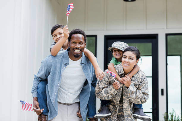 istock Dad and soldier mom give sons piggy back rides 1356431237