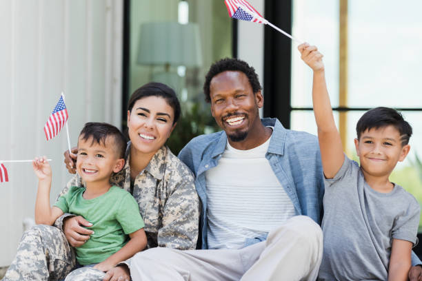 istock Sitting on front stoop, military family waves American flags 1356431239