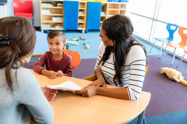 in der eltern-lehrer-besprechung lächeln erwachsene den jungen an - african descent male education indoors stock-fotos und bilder