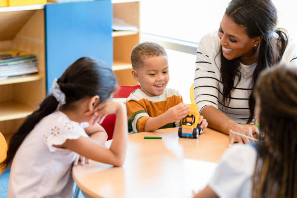 istock Smiling teacher and happy students sit together in class 1356433429