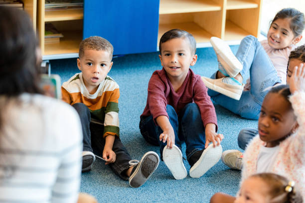 istock Preschool children listen as unrecognizable teacher reads book 1356433454