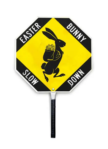 Easter themed traffic alert signal used by crossing guards and in work zones. Yellow and black metal textured sign with pole to hold. Isolated on white.