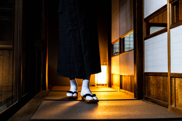 Traditional Japan Japanese house or ryokan with man in kimono walking closeup of legs with geta tabi shoes and white socks by shoji sliding paper doors and tatami mat Traditional Japan Japanese house or ryokan with man in kimono walking closeup of legs with geta tabi shoes and white socks by shoji sliding paper doors and tatami mat geta sandal photos stock pictures, royalty-free photos & images