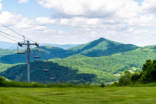 Sugar Mountain ski resort town park with view of Beech mountain and ski chair lift slope and green lush foliage and clouds in North Carolina Blue Ridge Appalachia