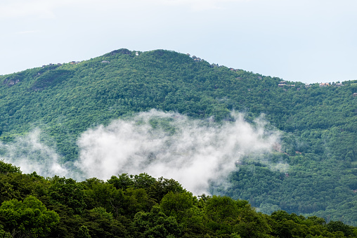 Ski resort town view of Beech mountain and rising clouds mist fog over forest green summe trees in North Carolina Blue Ridge Appalachia Smokies Smoky