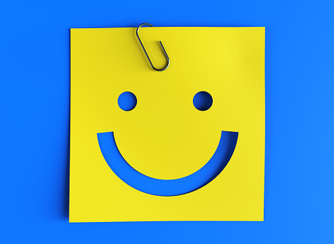 Happy smiling emoticon on a yellow paper