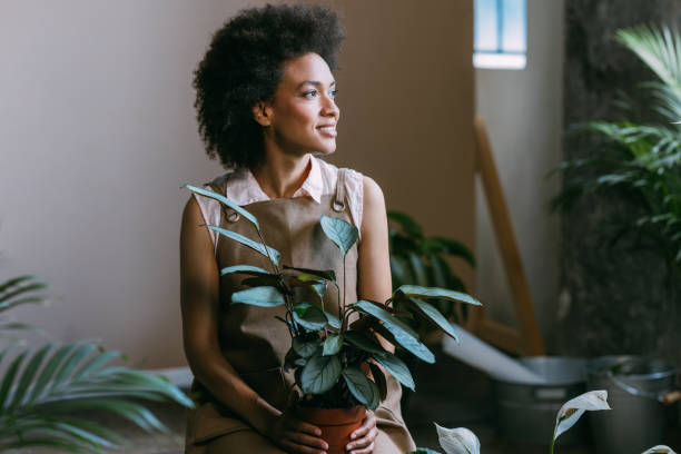 istock Smiling Female Florist Sitting in her Workshop Surrounded with Plants 1356438174