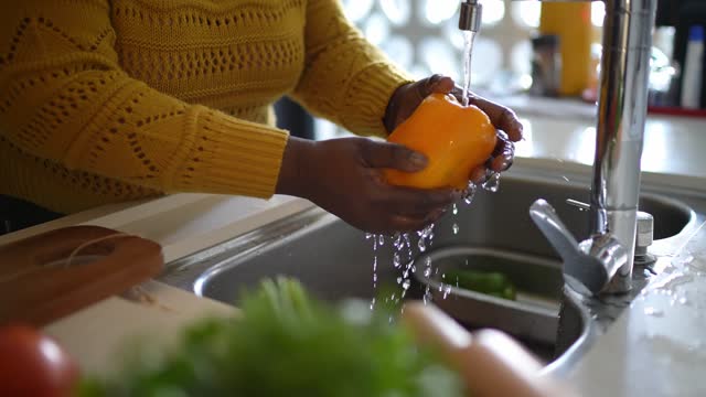 Close-up of a senior woman's hands washing a bell pepper at home