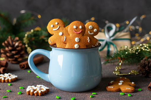 Homemade gingerbread cookies in the form of fabulous gingerbread men and christmas trees in blue cup in new year composition, Close-up
