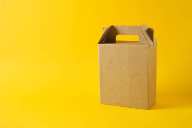 istock cardboard box on a yellow background, gift box without logo, blank packaging for your design 1356449872