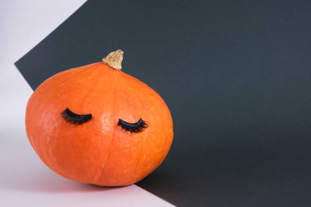 istock pumpkin with false eyelashes on a dark green background 1356450525