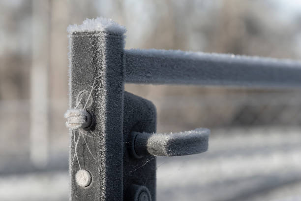 Handle of open metal gate covered in ice crystals on sunny winter day