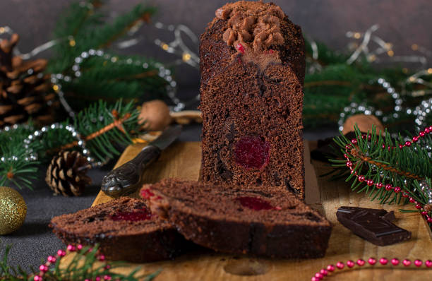 istock Sliced christmas cupcake with cherries and chocolate covered with chocolate icing on wooden board on new year background, Close-up 1356452152