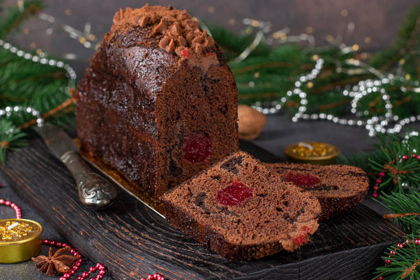 istock Sliced christmas cupcake with cherries and chocolate covered with chocolate icing on wooden board on new year background, Close-up 1356453075