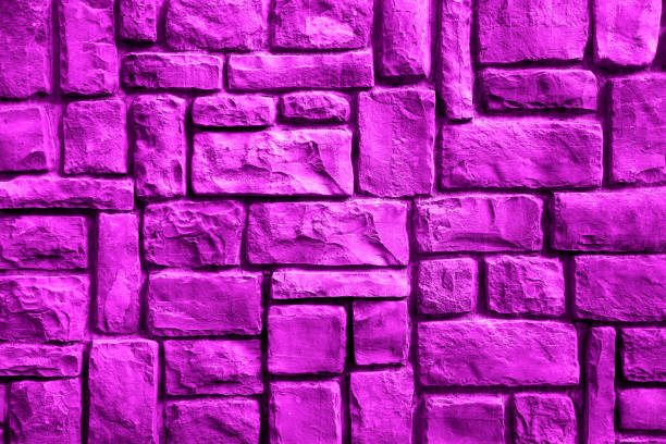 Texture of a stone wall made of rectangular blocks of different sizes painted in violet as a background