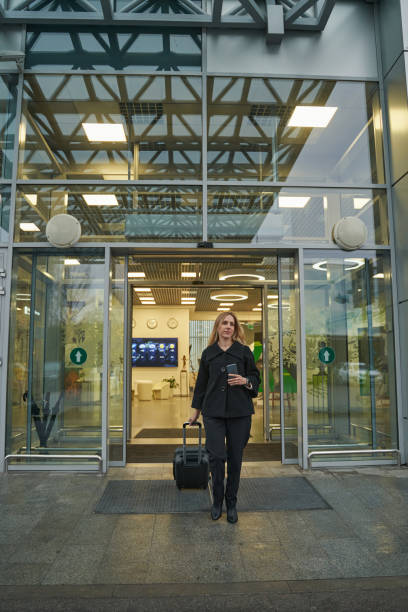istock Traveler exiting airport building with her baggage 1356455064