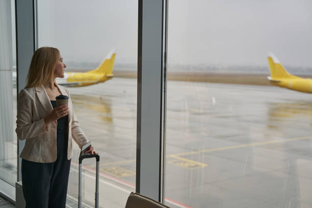 istock Female watching airplane on takeoff strip from window 1356455104