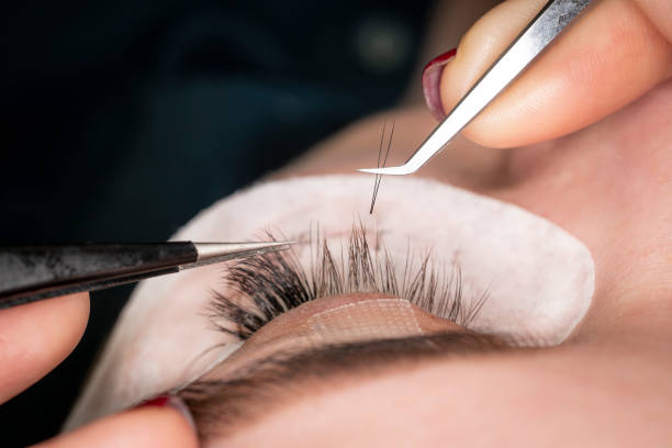 Permanent makeup. Eyelash Extension Procedure. Eye with Long Eyelashes. Professional stylist lengthening female lashes. Eyelash extension procedure - master and a client in a beauty salon close-up. primer plano de maquillaje permanente. procedimiento de extensión de pestañas. ojo con pestañas largas. estilista profesional alargando pestañas femeninas. procedimiento de extensión de pestañas - maestro y un cliente en un salón de belleza