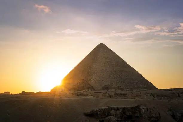 Archaeological complex of the Great Egyptian Pyramids is located on the Giza plateau. Pyramids of Chephren Khafra in the night light at sunset. sun sets behind the pyramid.